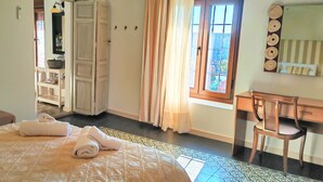 A bedroom with a bed, a desk, a chair, a wardrobe, and a bathroom area.