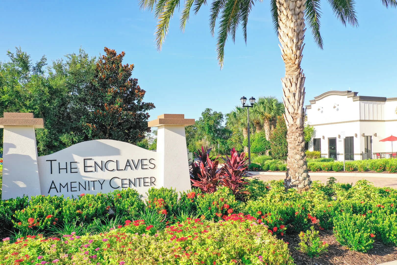 The Enclaves Amenity Center sign with a landscaped garden in front.