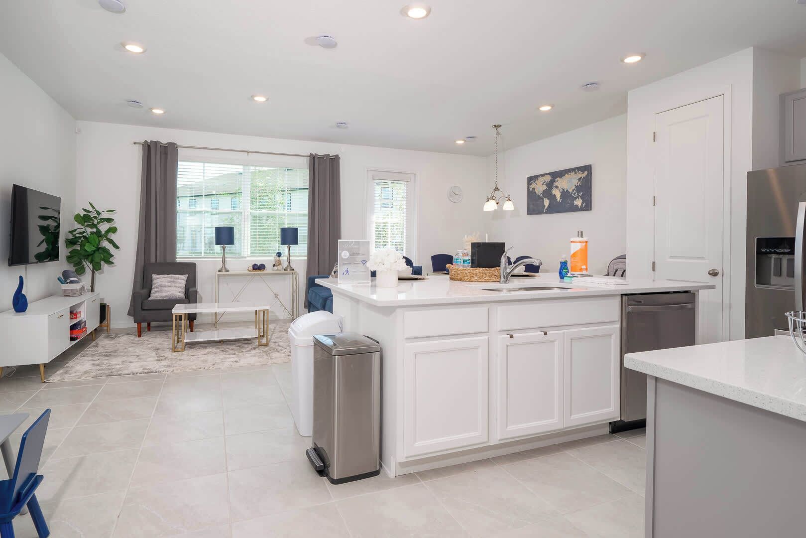 A modern kitchen with white cabinetry, a stainless steel refrigerator, and a built-in dishwasher.