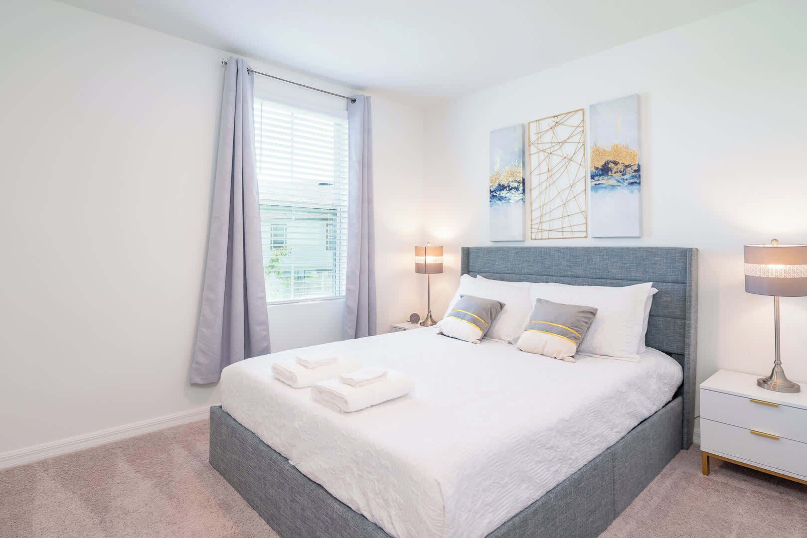 A neatly made bed with pillows and a bedside table with a lamp.