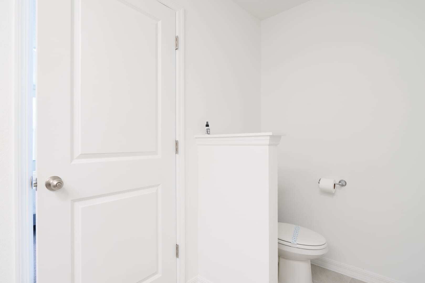 Een witte badkamer met een toilet en een deur.