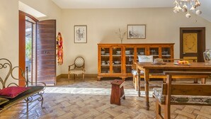 Zona pranzo con tavolo in legno, sedie e un mobiletto con vetrate.