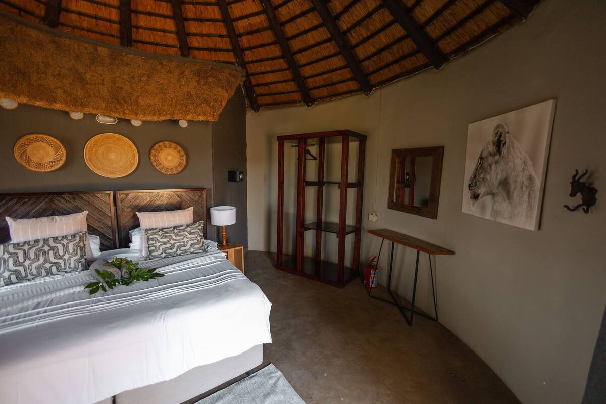 A bedroom with a bed, a wooden cabinet, a mirror, and a wall with three woven baskets.