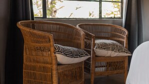 Two wicker chairs with patterned cushions in a room with a large window. - Nsala Wilderness Camp (Hoedspruit)