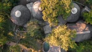 An aerial view of a property with multiple stone structures, possibly for accommodation, surrounded by dense greenery and a small water feature. - Nsala Wilderness Camp (Hoedspruit)