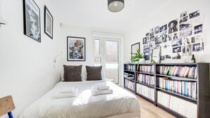 Una camera da letto con un letto, cuscini, una libreria e una parete di fotografie.