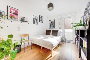 Une chambre à coucher avec un lit, une chaise, une bibliothèque et divers tableaux encadrés accrochés au mur.