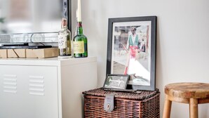 Un mobile bianco con una stampante Toshiba, due bottiglie di alcolici, una cornice con foto e un cesto in vimini con un'etichetta.