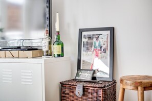 A white cabinet with a Toshiba printer, two bottles of alcohol, a framed photo, and a wicker basket with a label.