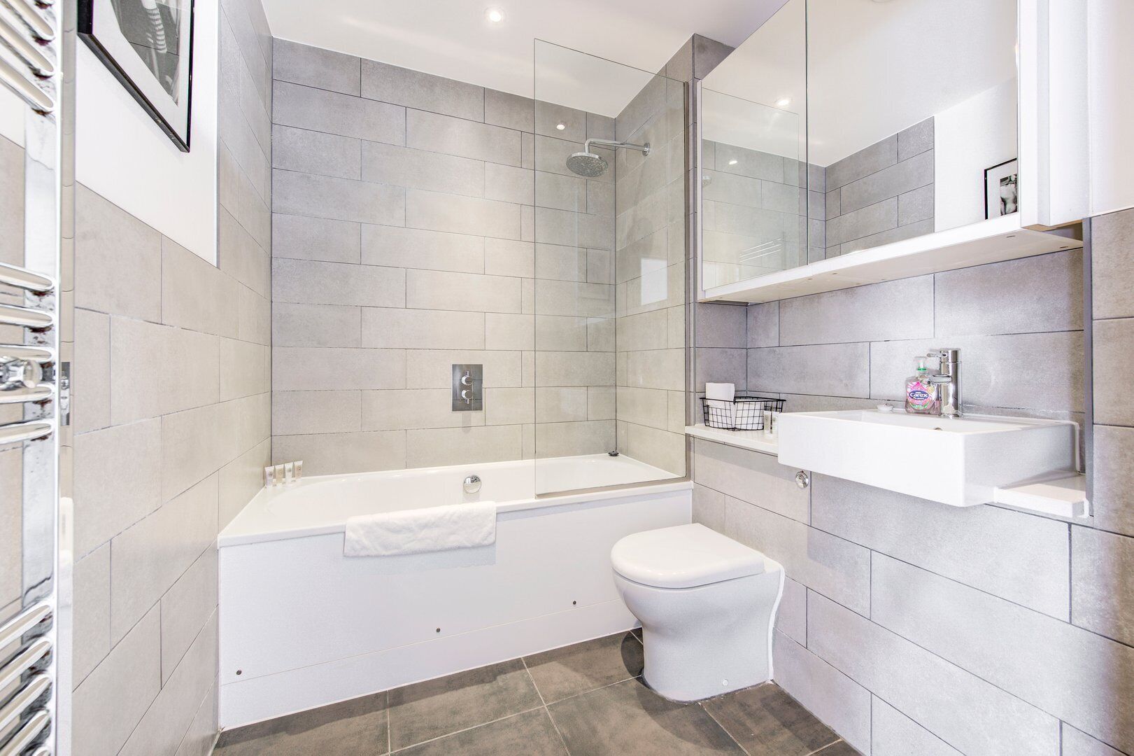 A modern bathroom with a bathtub, toilet, and a glass-enclosed shower area.