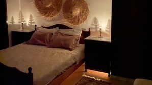 Un dormitorio con una cama, dos mesitas de noche y un adorno en la pared.