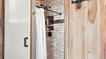 A rustic bathroom with a wooden wall, a white door, and a towel rack.