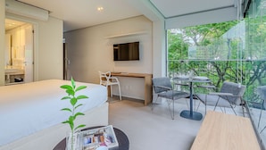 A modern hotel room with a bed, desk, and balcony with a view. - Next Home Design by Viva - Apartamentos em prédio próximo ao Parque do Ibirapuera (São Paulo)