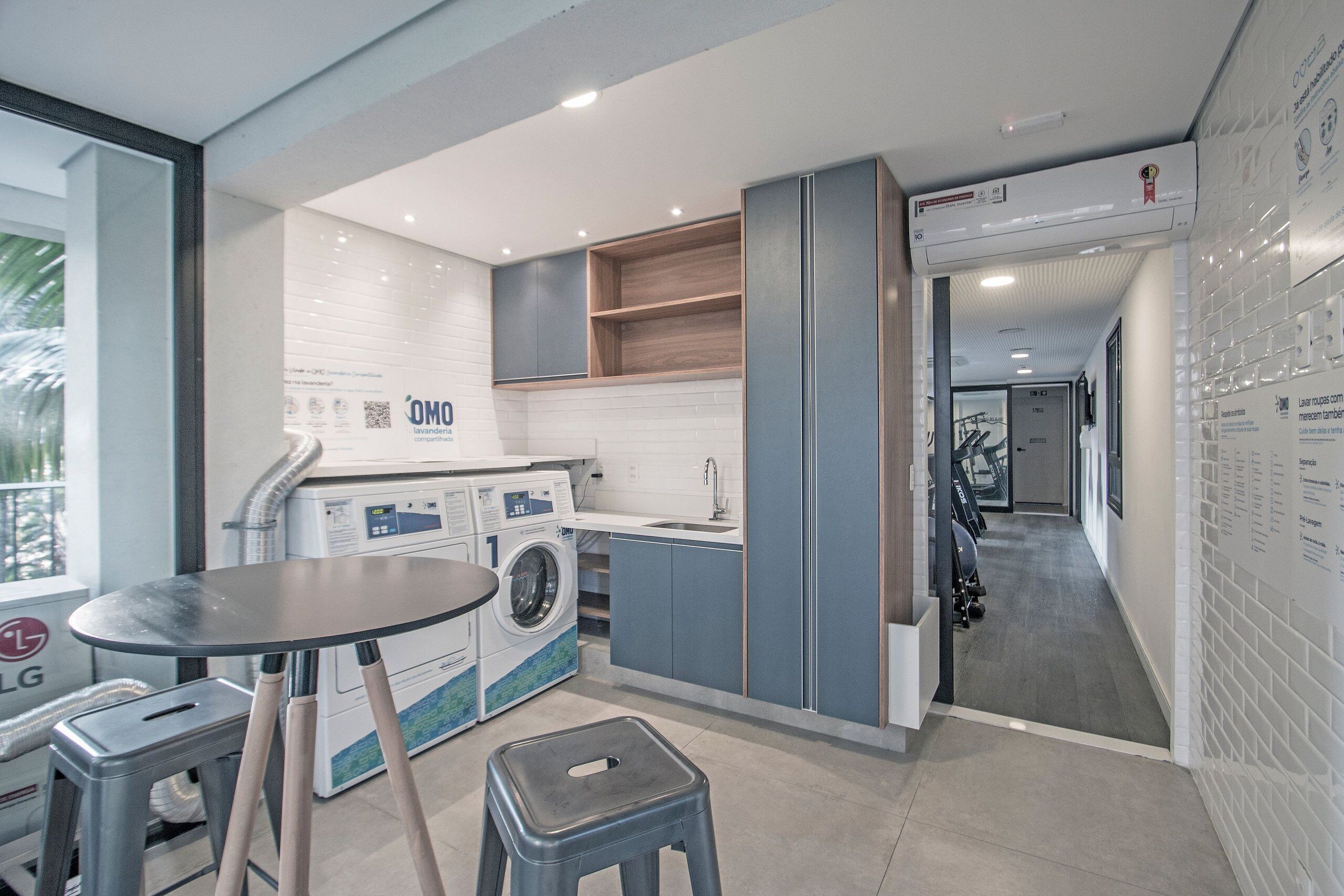 A modern kitchen with a washing machine, a table, and stools.