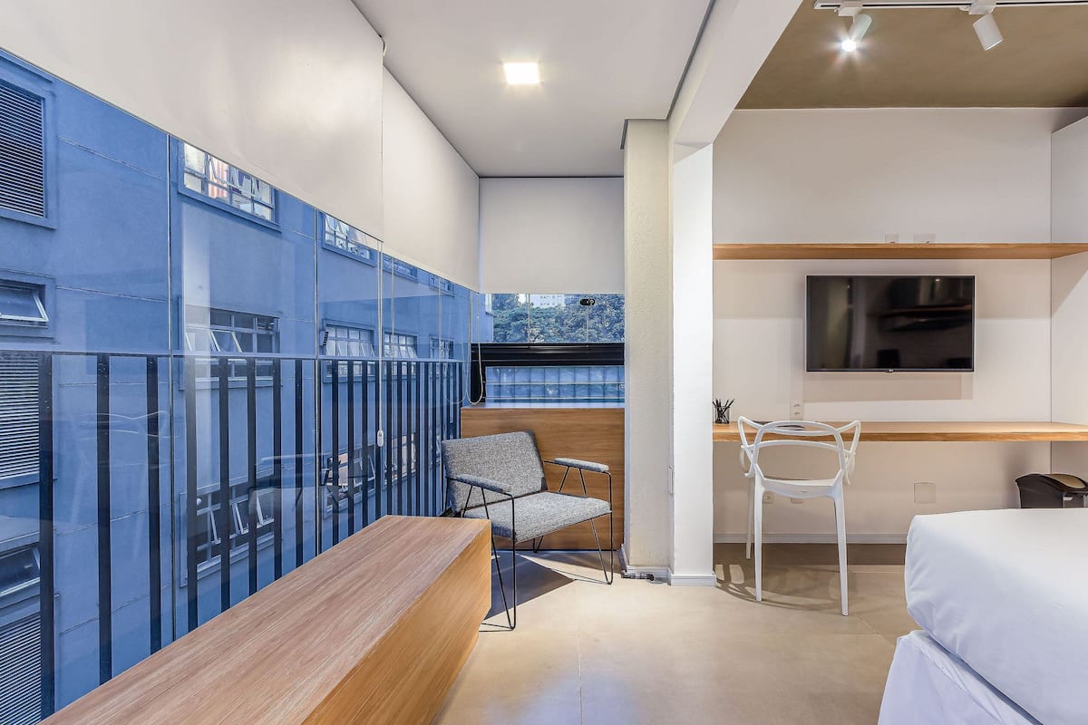 A modern room with a wooden desk, two chairs, a bed, and a TV.