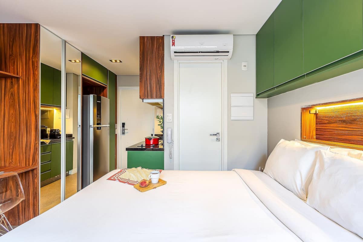 A hotel room with a bed, a breakfast tray, a kitchen area, and a green wall.