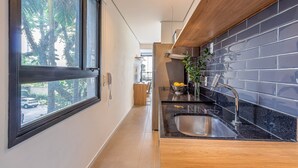 A modern kitchen with a large window, a sink, and a countertop. - Next Home Design by Viva - Apartamentos em prédio próximo ao Parque do Ibirapuera (São Paulo)