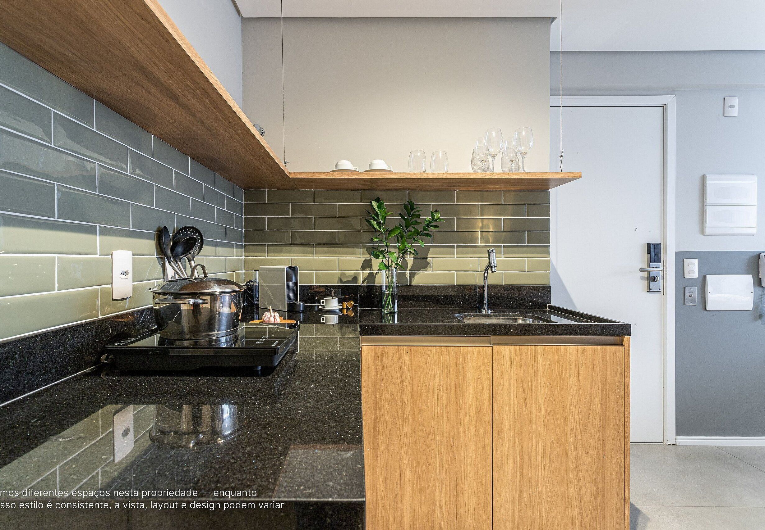 A modern kitchen with a black granite countertop, wooden cabinets, and a backsplash of grey tiles.