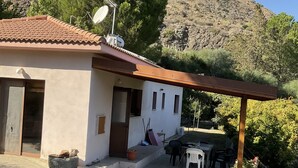 A small house with a tiled roof, a satellite dish, and a patio area with a table and chairs. - Beautiful 3 Bedr House in Arakapas With Fireplace (Arakapas)