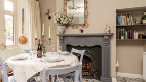 Une salle à manger avec une cheminée, une table dressée pour quatre personnes et une bibliothèque remplie de livres.