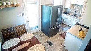 Une cuisine compacte équipée d’un réfrigérateur, d’un évier et d’un coin repas avec une table et des chaises.