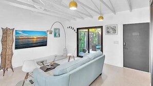A modern living room with a light blue sofa, a dining table, and pendant lights.