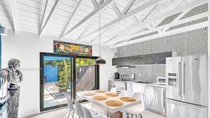 A modern kitchen with a dining area, featuring a large table with chairs, a refrigerator, and a microwave.