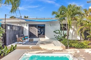 Uma casa moderna com piscina, móveis de pátio e área externa coberta.