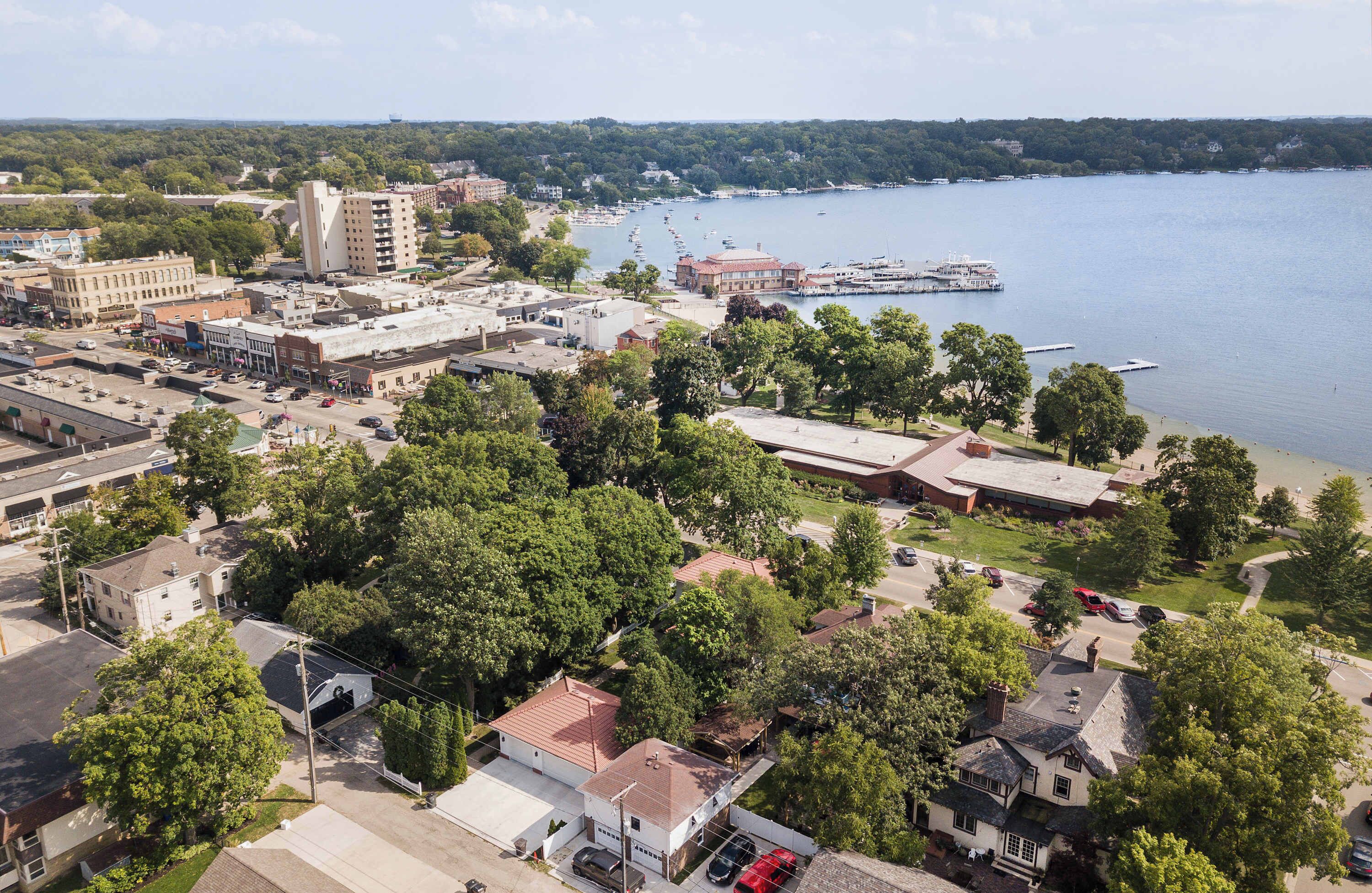 An aerial view of a town with a waterfront, including buildings, roads, and a dock with boats.