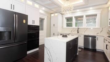 A modern kitchen with white cabinetry, a marble island, and stainless steel appliances.