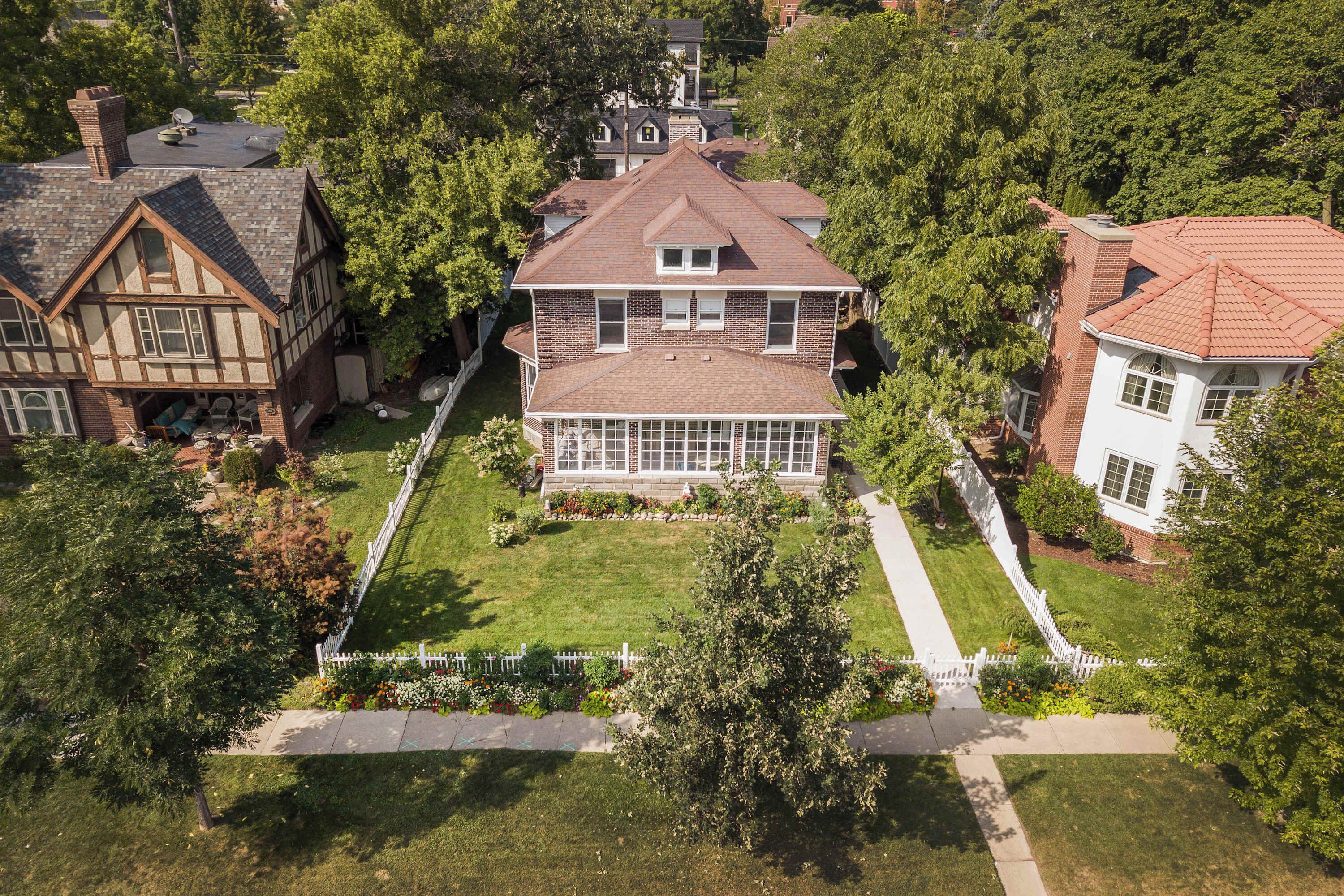 A large house with a prominent front porch, a garage, and a well-maintained lawn.