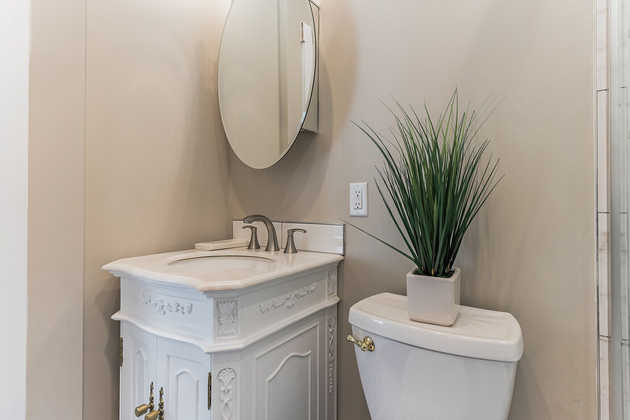 Een badkamer met een witte wastafel, een wastafel, een spiegel en een toilet.