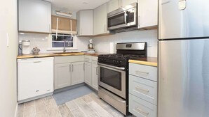 A modern kitchen with stainless steel appliances, white cabinetry, and a wooden countertop. - Chic Lake Geneva Apartment in Desirable Location! (Lake Geneva)