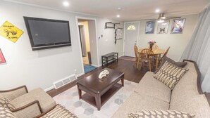 A living room with a sofa, a coffee table, and a TV mounted on the wall. - Chic Lake Geneva Apartment in Desirable Location! (Lake Geneva)