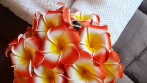 Ein graues Sofa mit einem weißen Handtuch und einem Strauß aus roten und gelben Blumen.
