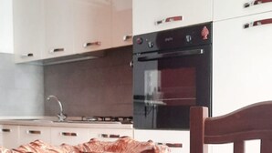 Eine Küche mit weißen Schränken, einem schwarzen Backofen und einem Holztisch.
