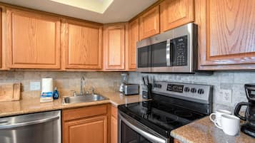 Eine Küche mit Holzschränken, Edelstahlgeräten, Granit Arbeitsplatten und einem eingebauten Backofen.