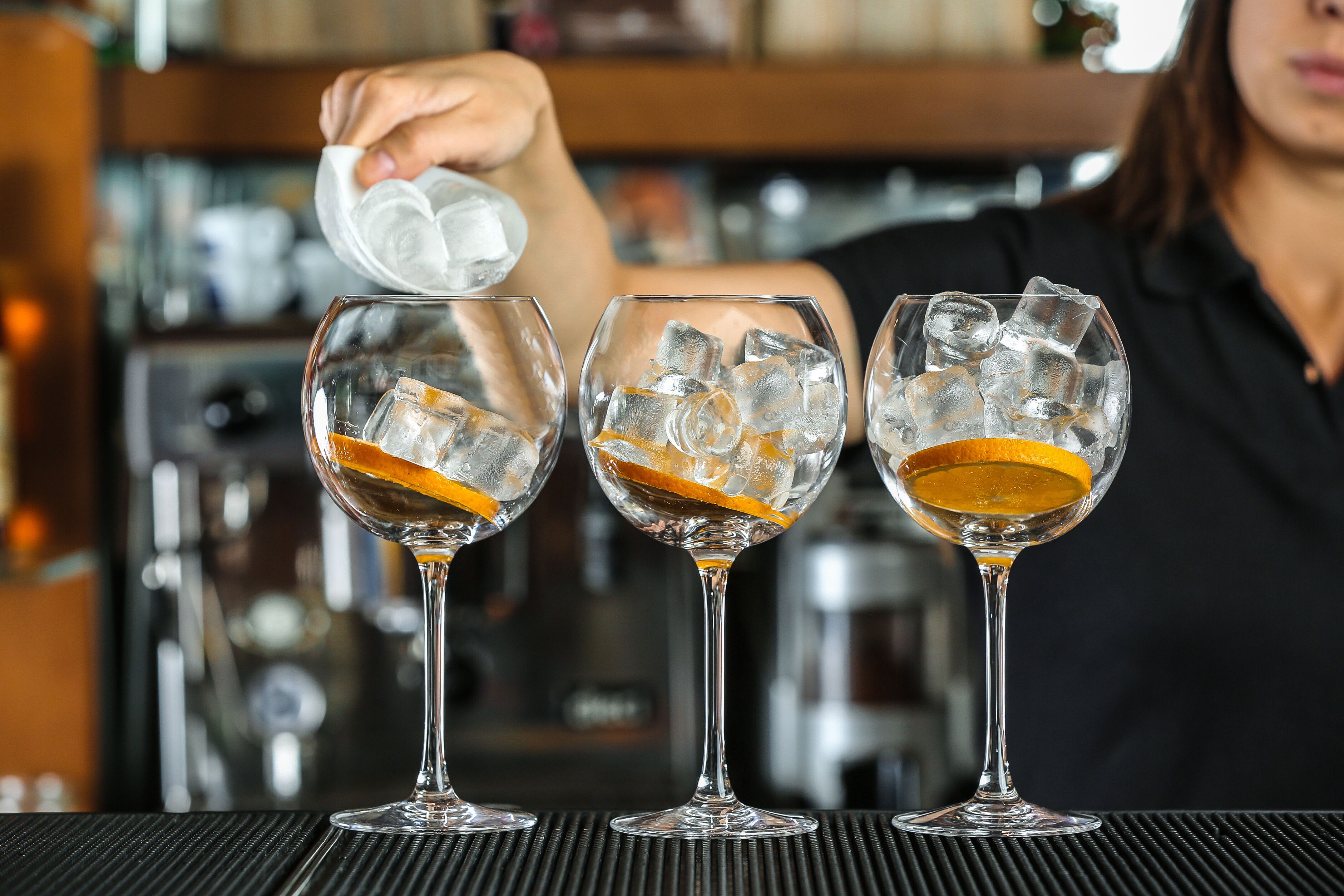 Three glasses with ice and orange slices on a bar counter.