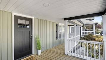 A wooden deck with a dark door and a white railing.