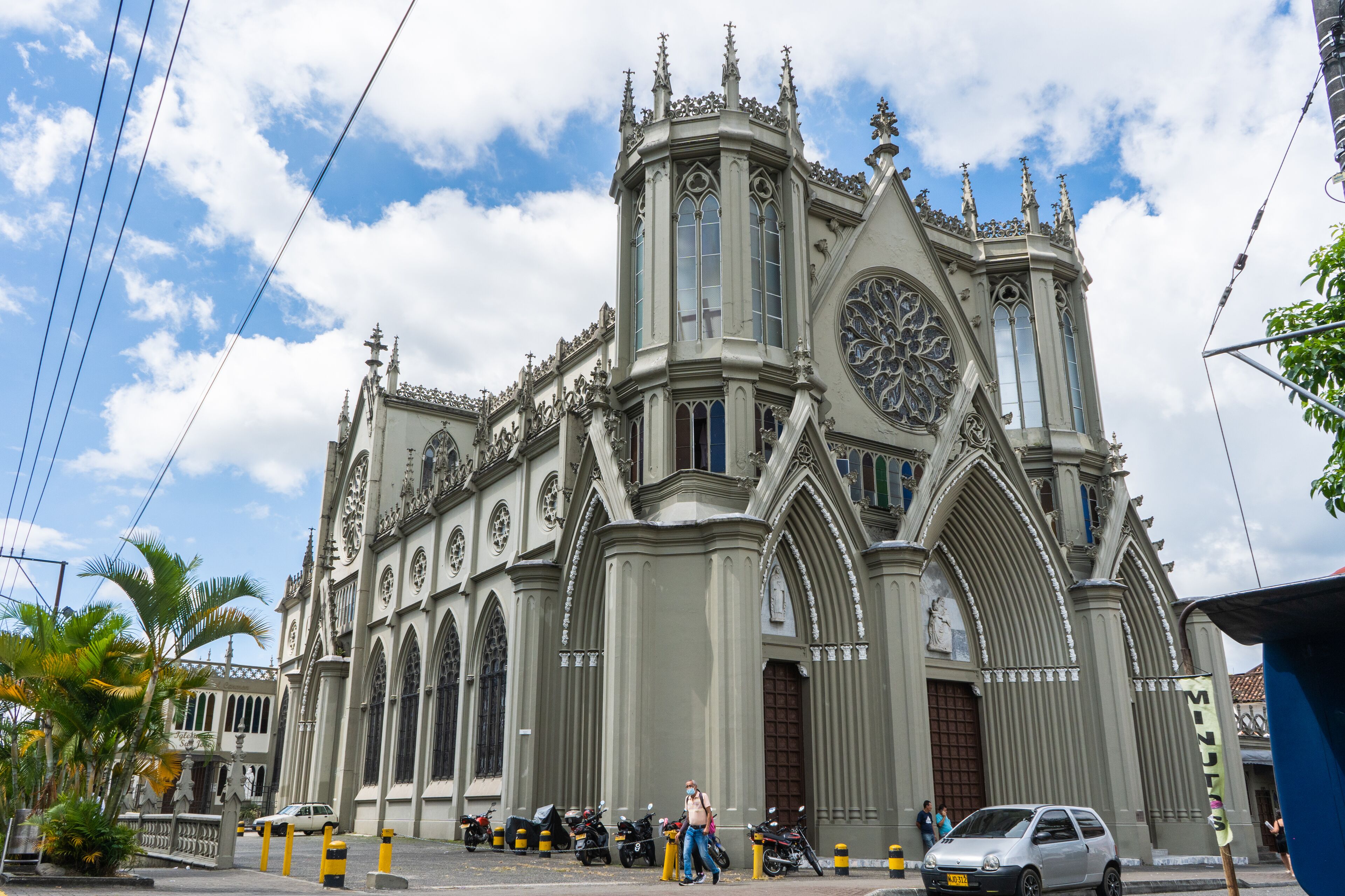 Una iglesia grande y ornamentada con una imponente torre de reloj y varios ventanales de arco.
