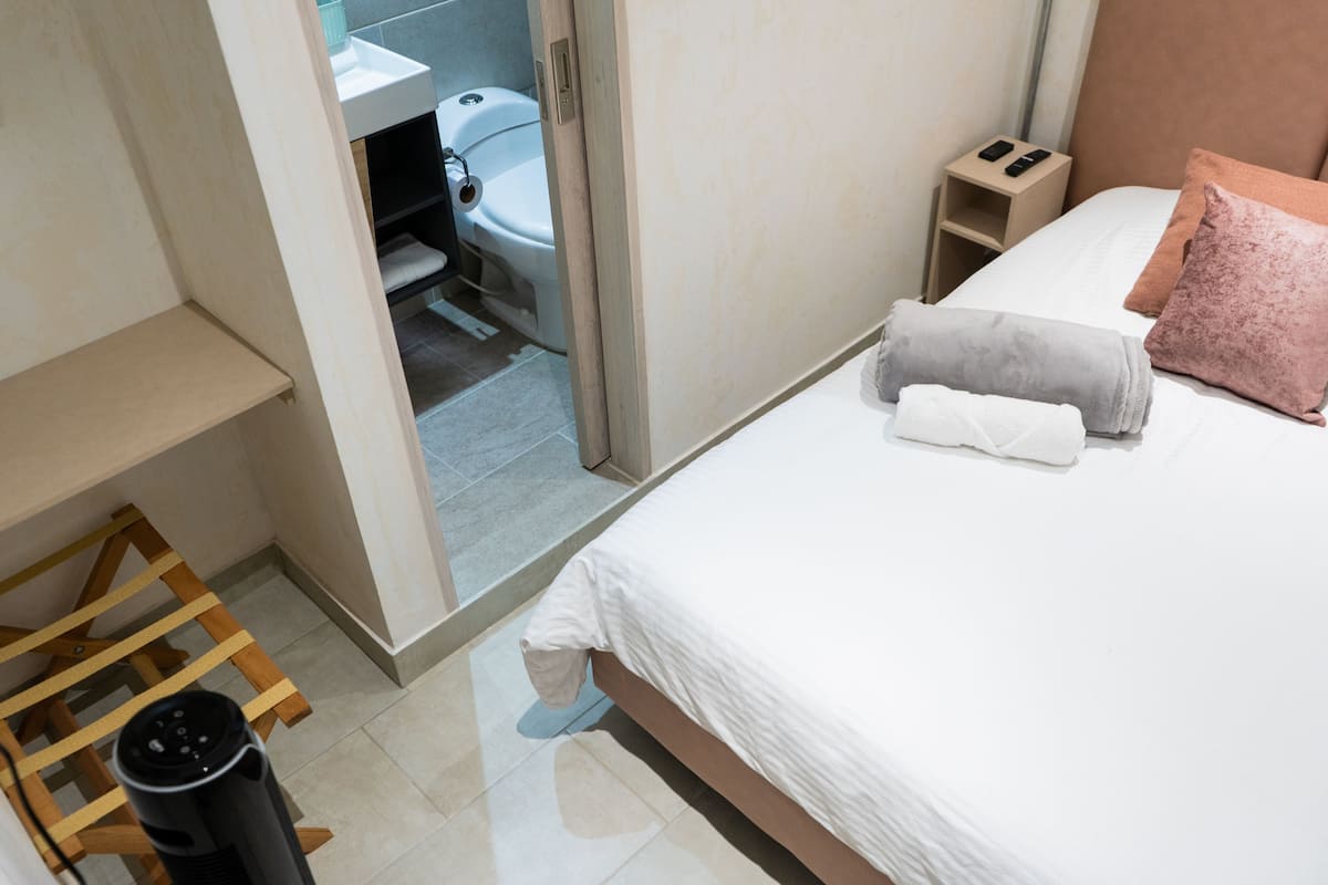 A hotel room with a bed, bedside table, and a view into the bathroom.
