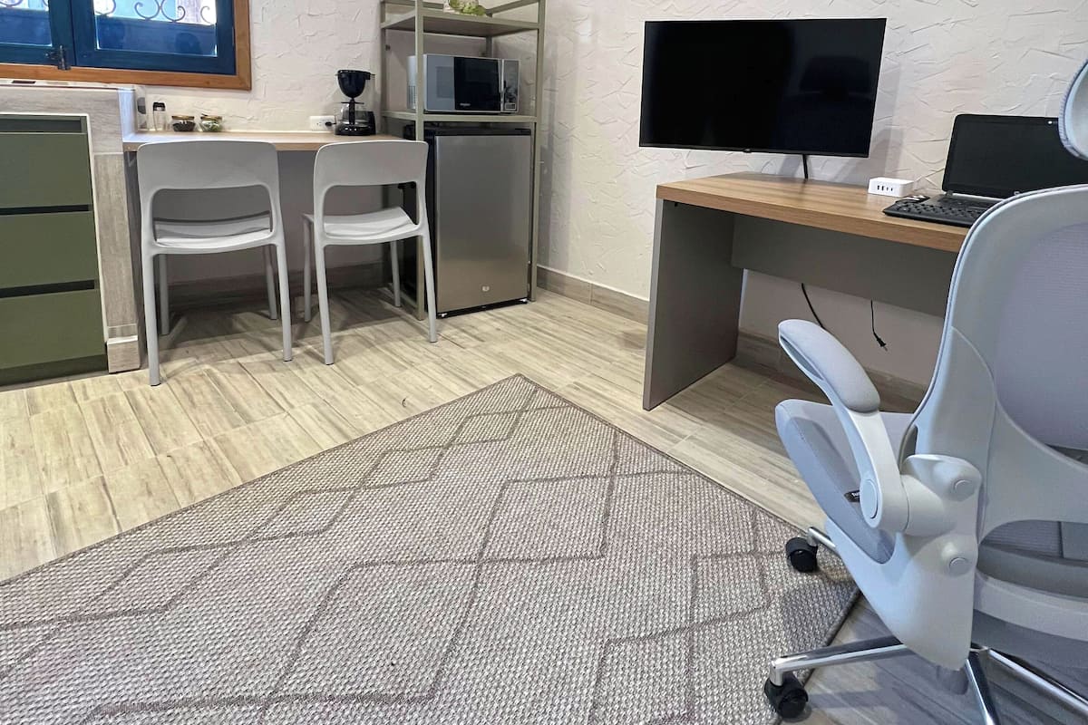 A modern office space with a desk, two chairs, a television, and a microwave.