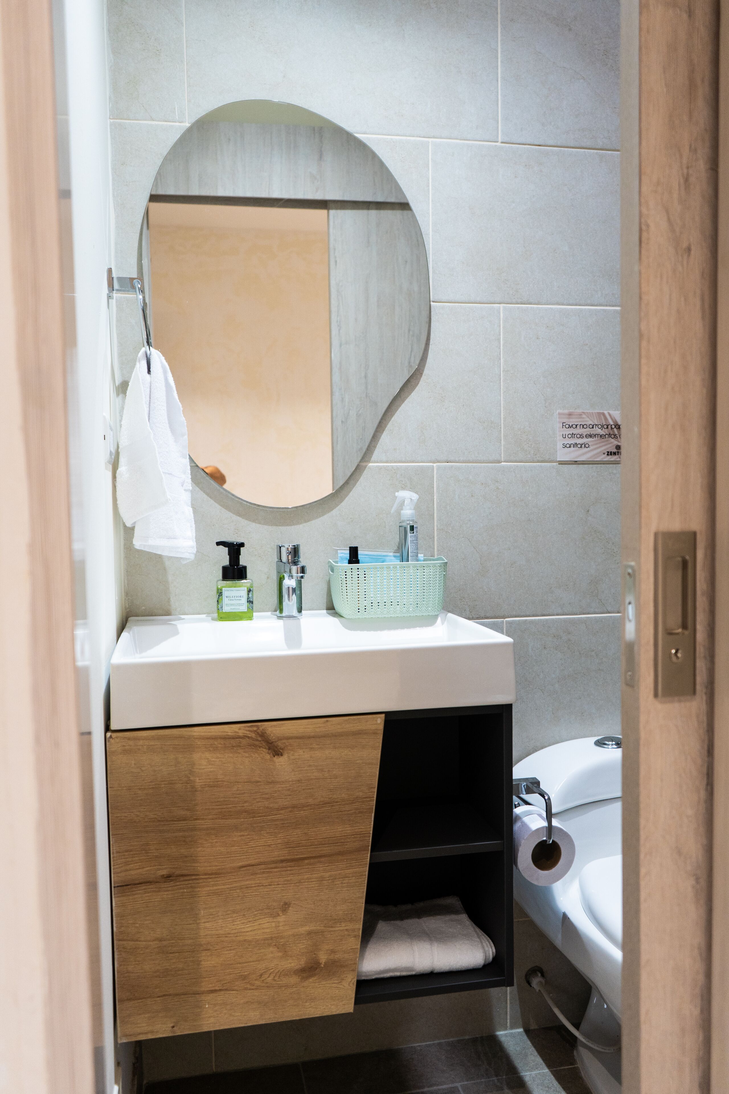 A bathroom with a white sink, a mirror, a towel rack, a basket, and a toilet.