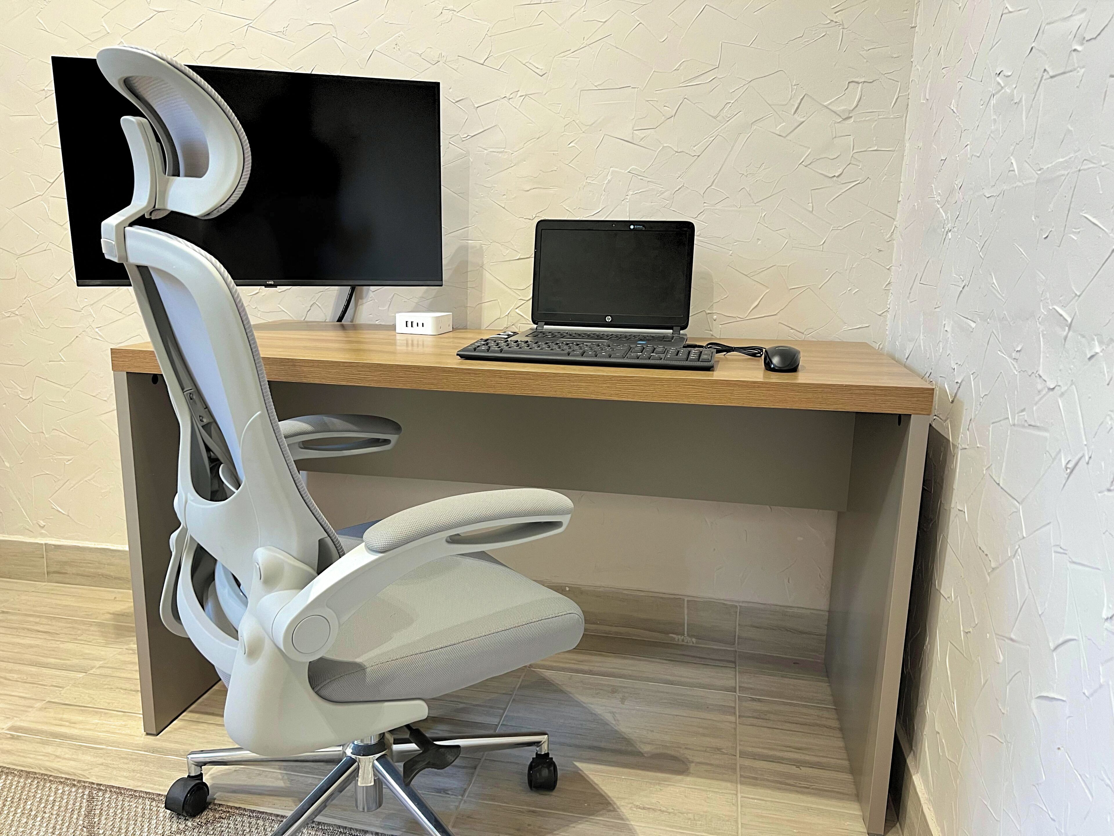 A modern office desk with a laptop, a monitor, and a chair.