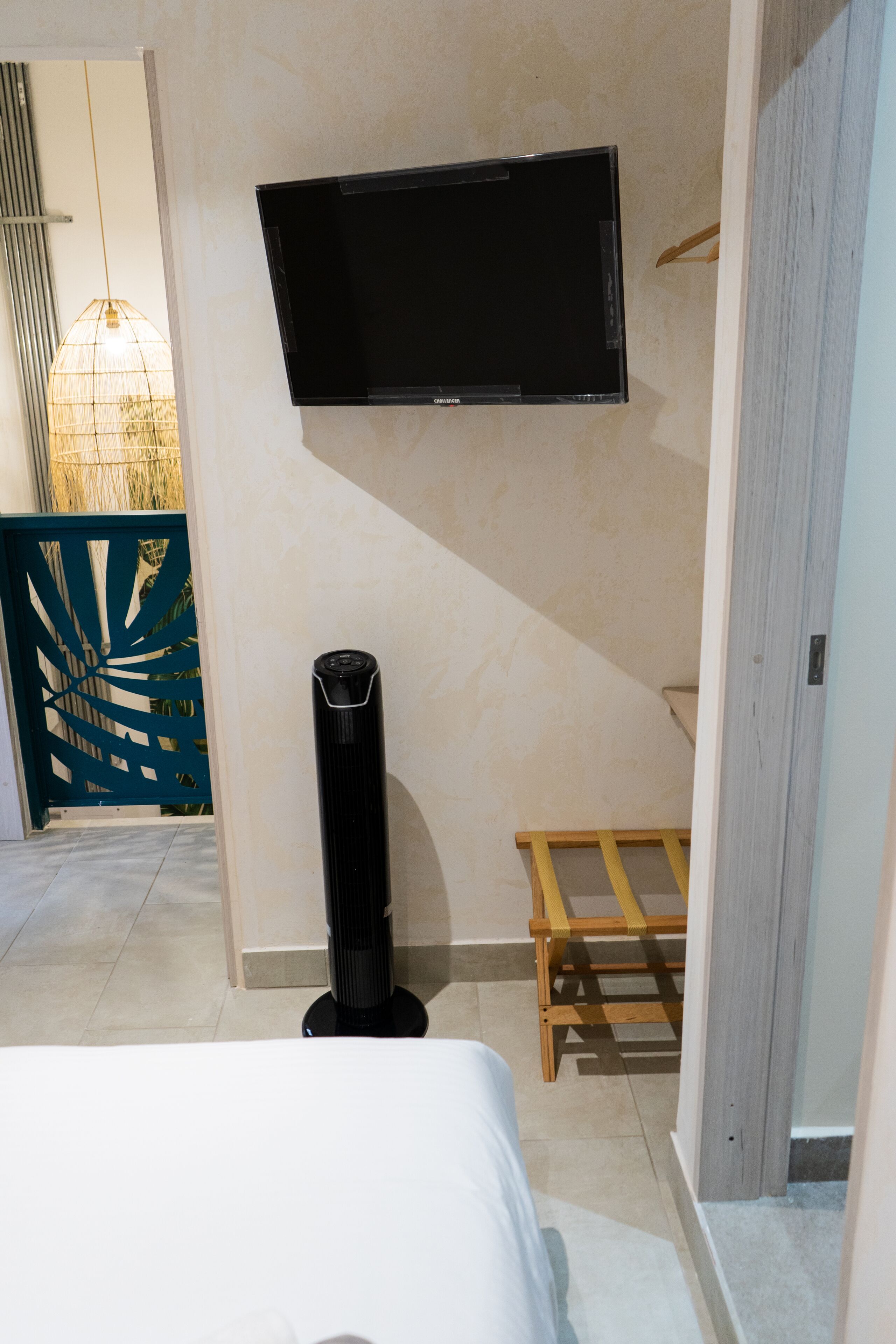 Un dormitorio con cama, un calentador portátil, un televisor montado en la pared y un banco de madera.