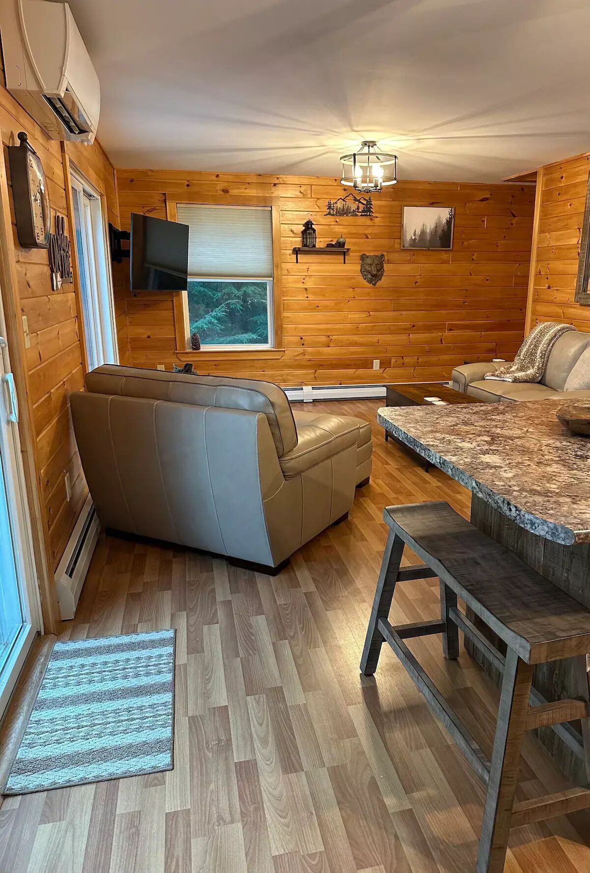 Interior acolhedor de uma cabana com sofá, mesa de jantar e televisão na parede.