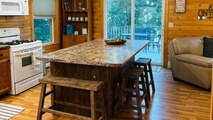 A kitchen with wooden cabinets, a granite countertop, a built-in stove, and a large island with stools.
