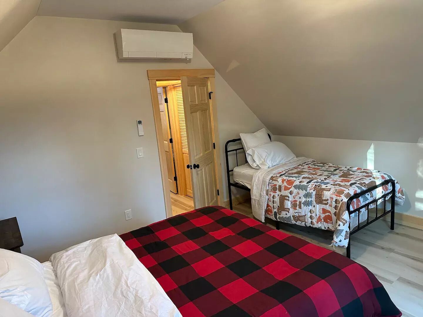 Ein Schlafzimmer mit zwei Betten, einer Holztür und einer Klimaanlage.
