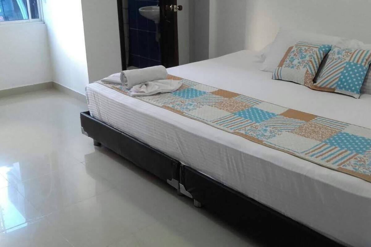 Een hotelkamer met een bed, een raam en een badkamer in de achtergrond.