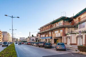Una calle con coches aparcados y edificios, incluyendo un hotel con un letrero que dice 'Le Cametelle'.
